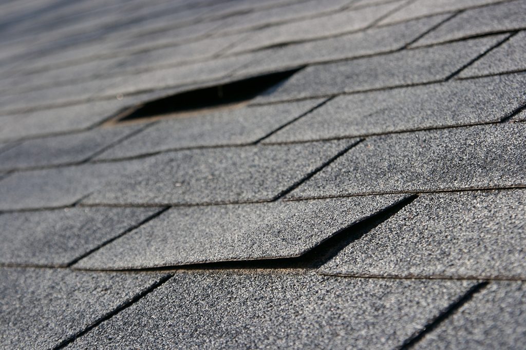 Closeup of a roof with damaged and missing shingles.