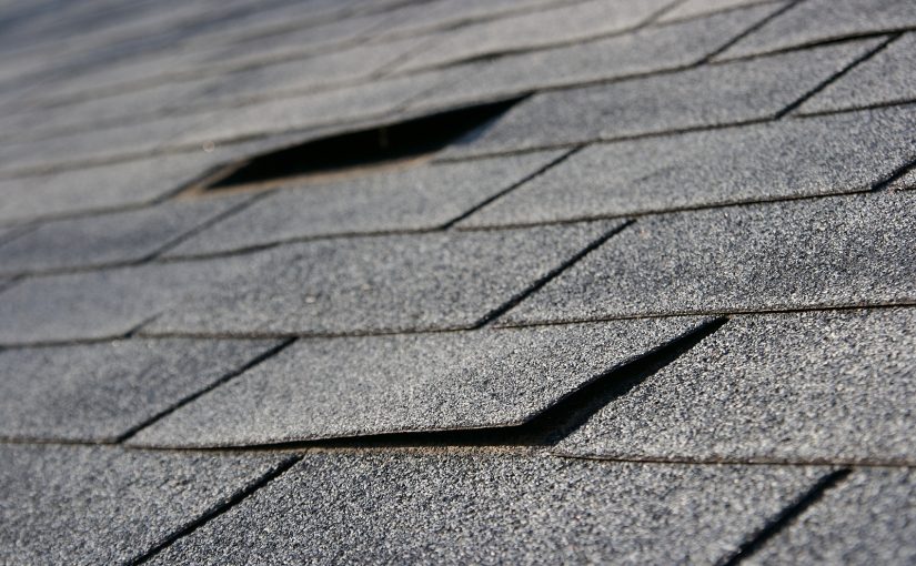 Closeup of a roof with damaged and missing shingles.