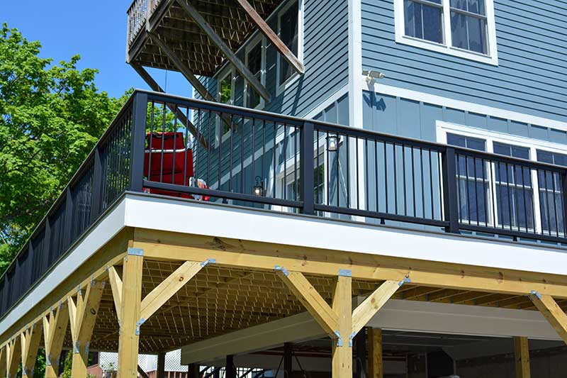 Angled shot of newly constructed home with wraparound porch, siding, windows, and more.