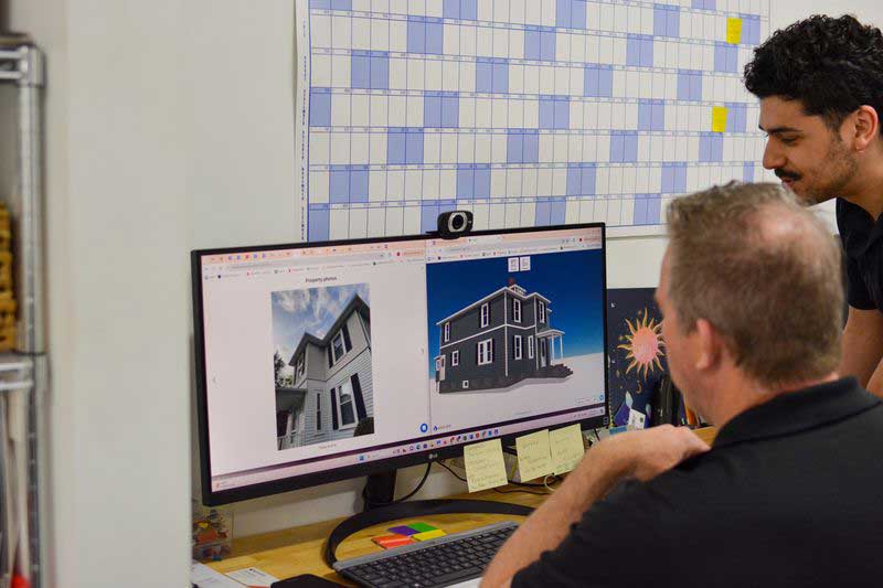 Patriot Contracting staff working on a desktop computer with a 3D model of a house.