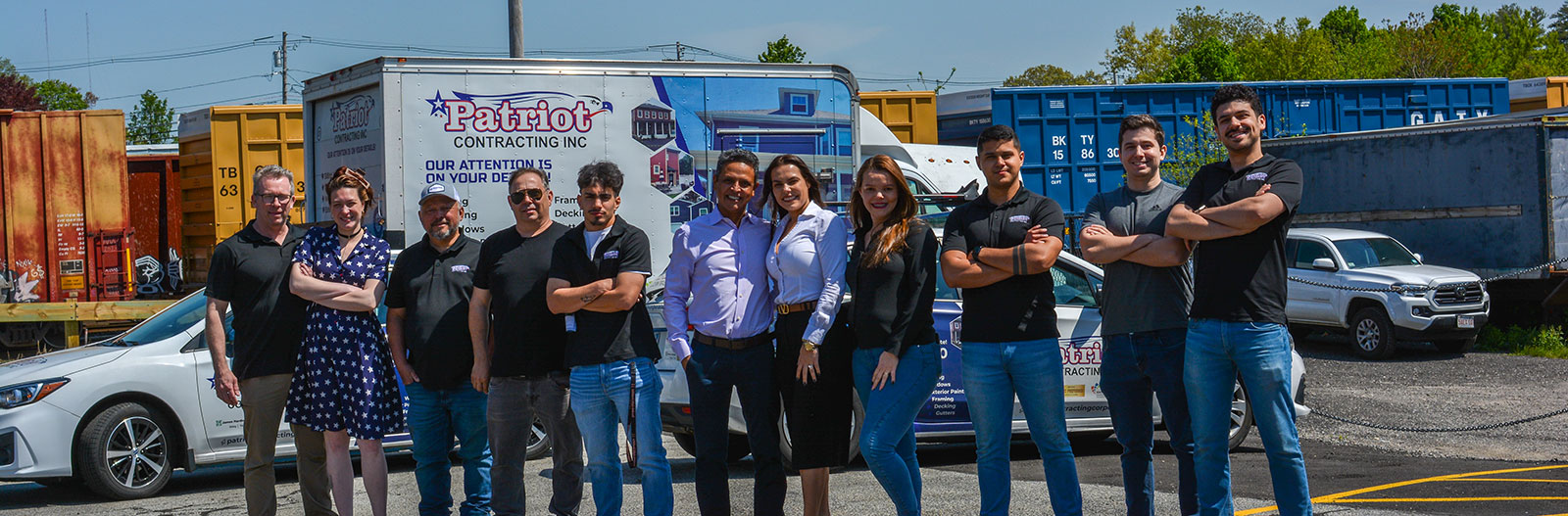 Group photo of Patriot Contracting staff standing in front of branded vehicles.