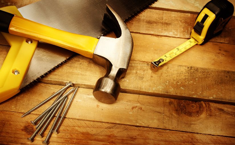 Saw, hammer, nails, and measuring tape as part of a home DIY project.