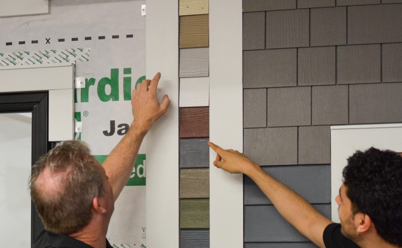 Two Patriot Contracting staff point out colors on a sample siding wall.